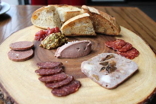 Housemade bread and charcuterie: clockwise from top, chicken liver pâté; Andalusian dry-cured chorizo; rabbit terrine with toasted walnuts, prunes and tarragon; harissa-spiced lamb salami; summer sausage, with guajillo chile and cherry lambic